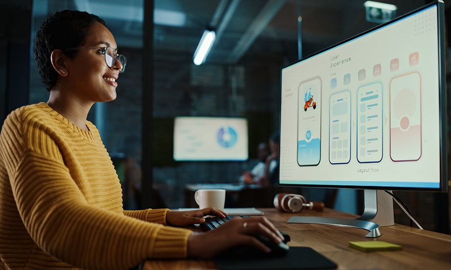 Frau vor Laptop mit UX/UI-Templates auf dem Bildschirm im Format 920x550
