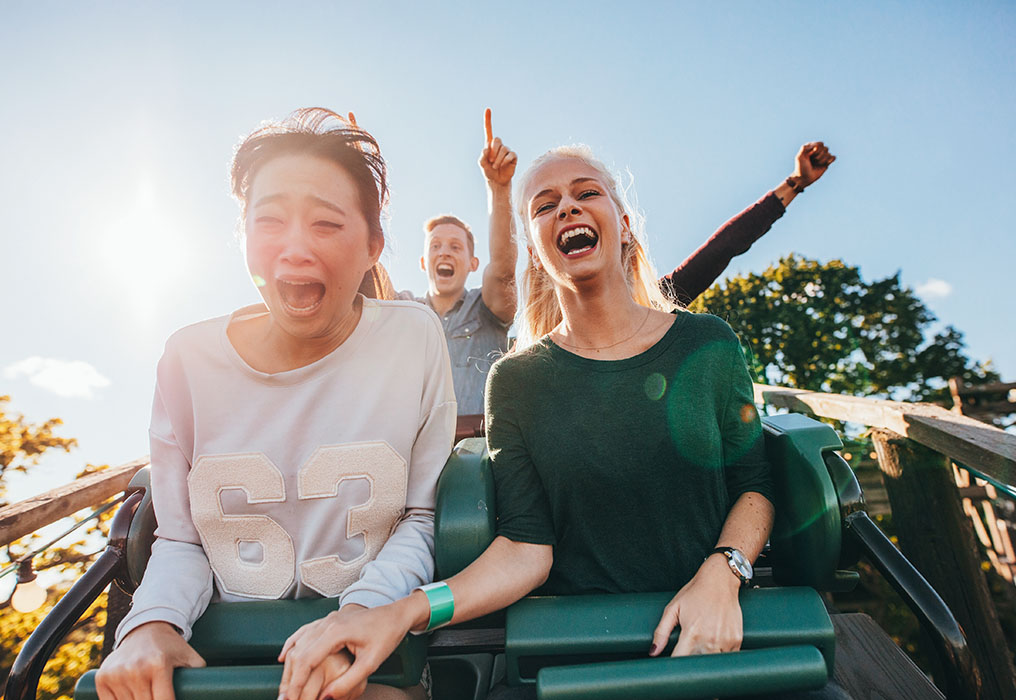 Three people sit in a roller coaster and have fun
