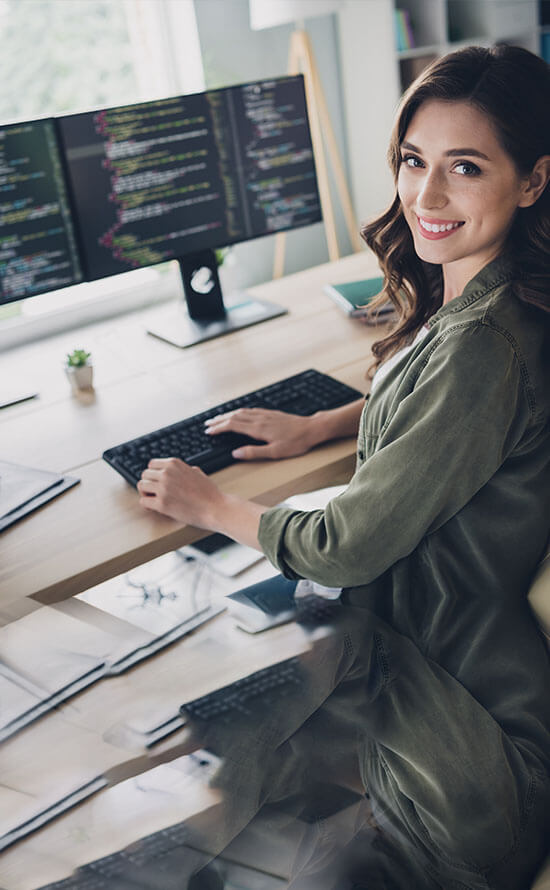 Woman at desk in front of screens with code