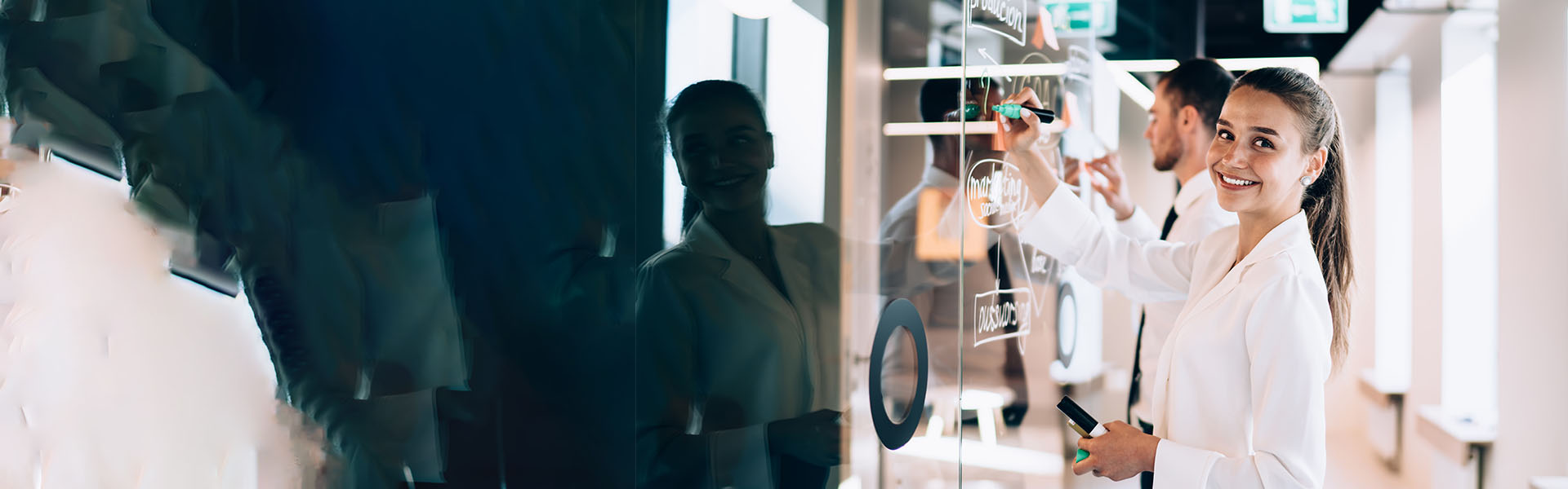 Frau in Büro vor Glaswand skizziert Projektplan