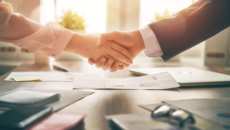 Mission-Zusammenarbeit Handshake zwischen zwei Personen über einem Bürotisch